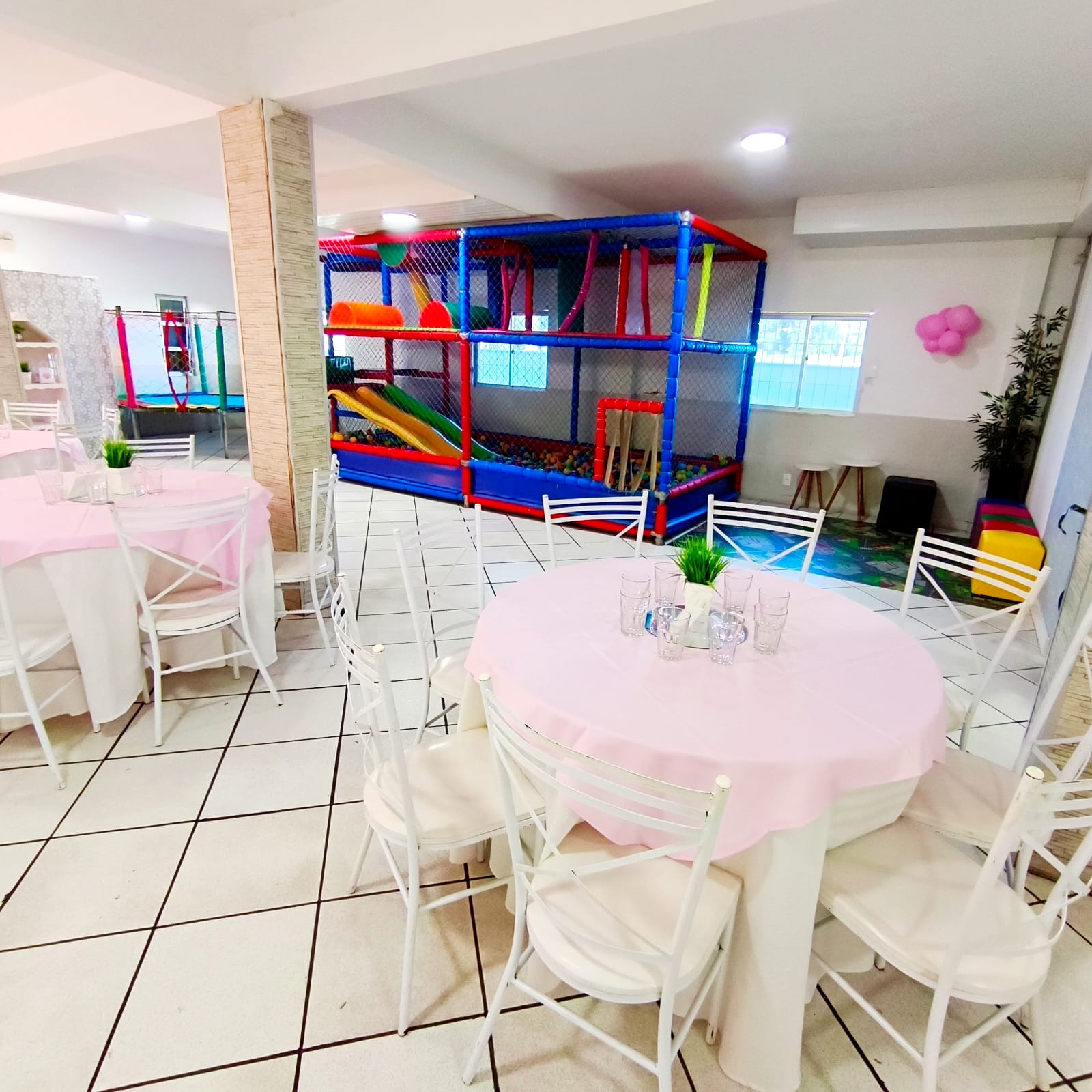 Salão da Miloca Festas com mesas rosas e playground indoor ao fundo
